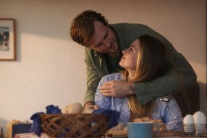 Ett par som omfamnar varandra vid ett frukostbord i ett ljust hem.