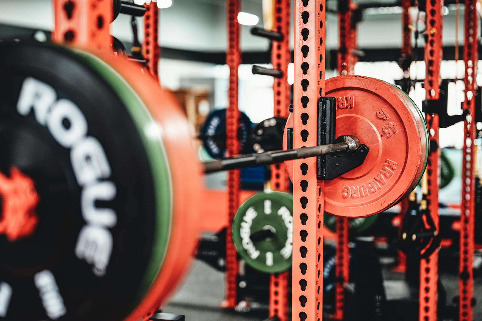 Röd skivstångsställning med tunga viktskivor i ett professionellt gym.